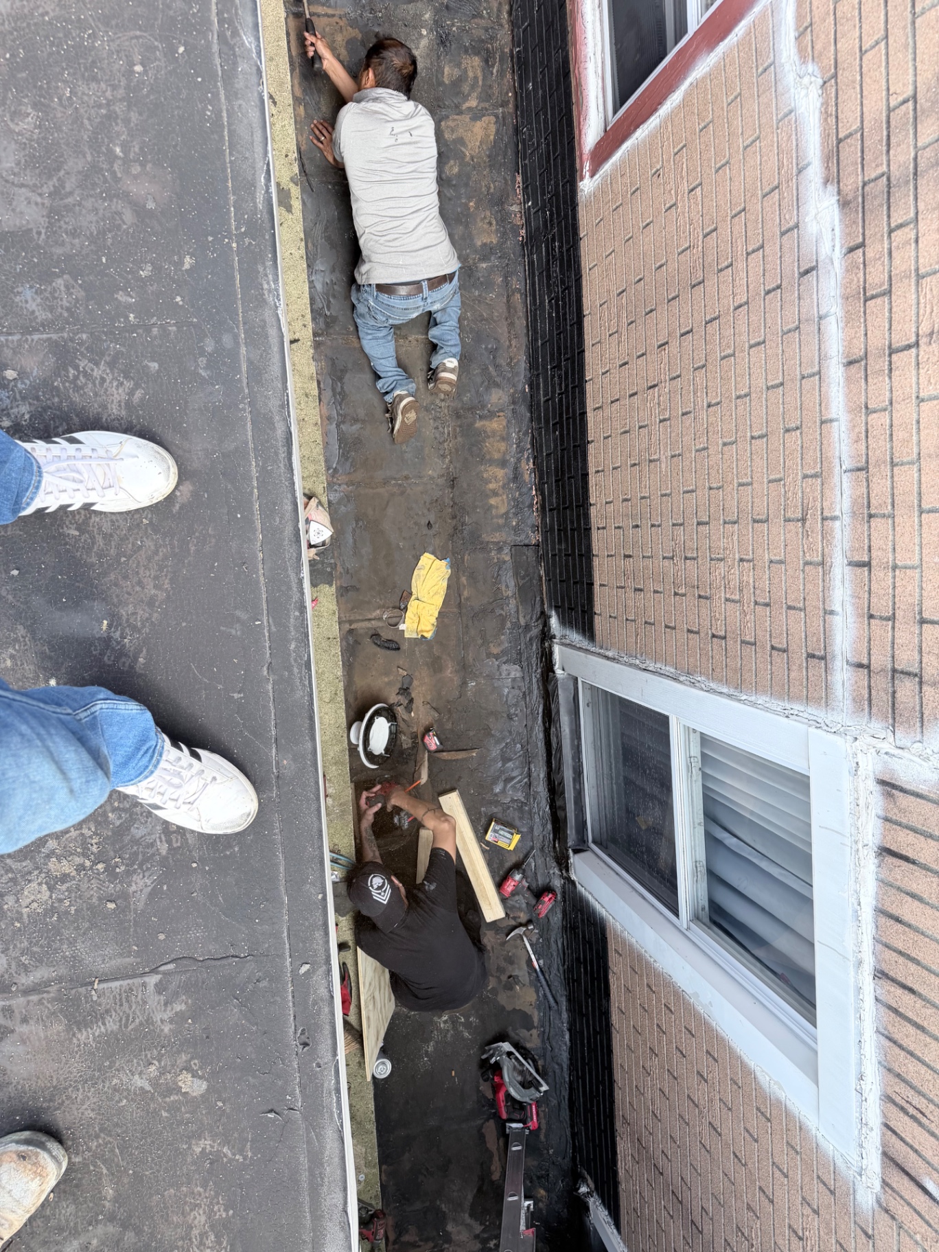 Crew preparing the flat roof surface by hand