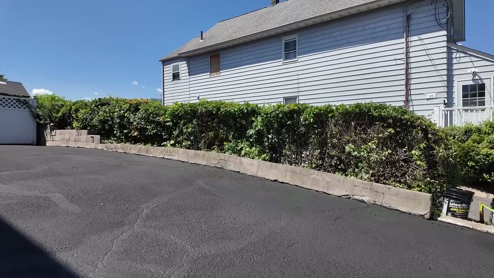 The same driveway after crack repair and sealcoating, smooth and uniform black